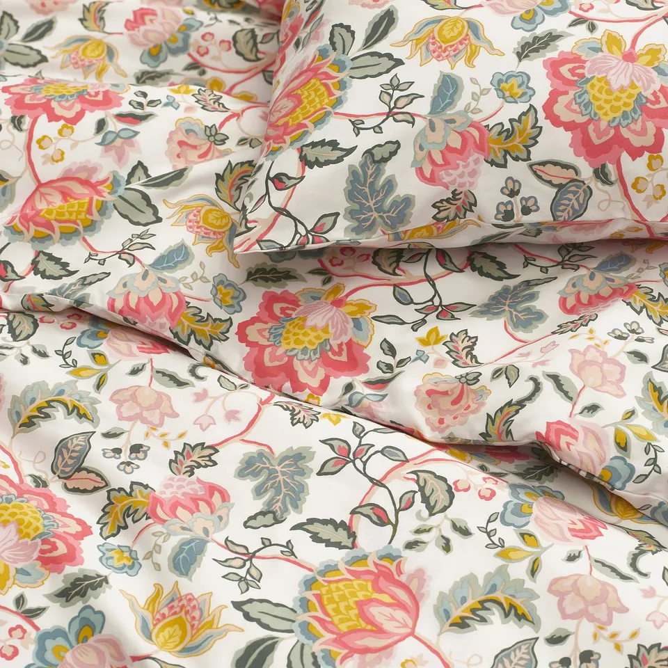 Floral bedsheet close-up, vibrant multi-color flowers on white, smooth texture, folded neatly.