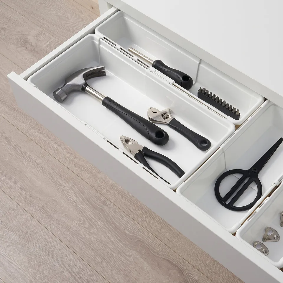 Open-top drawer filled with tools: hammer, wrenches, pliers, and scissors, showcasing organised storage.