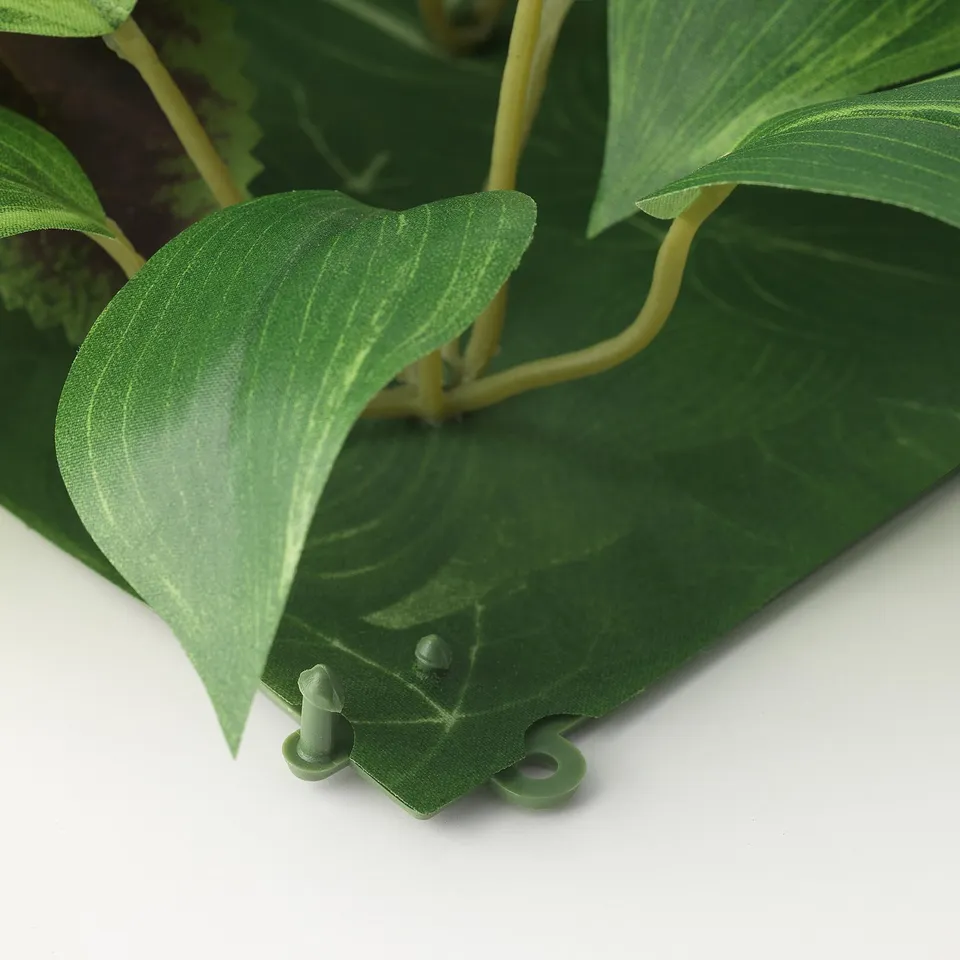 Artificial plant wall panel, made with recycled plastic, showcasing green leaves and a sturdy base.