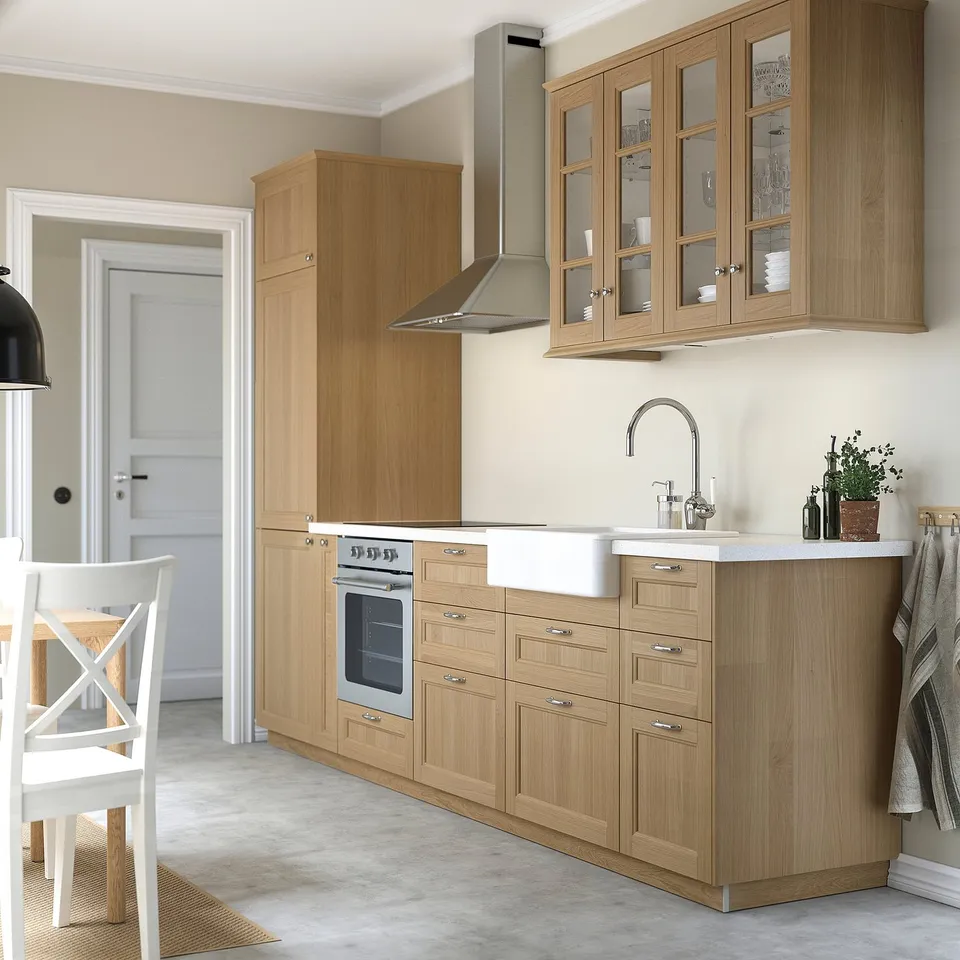 Modern kitchen with light wood cabinets, stainless steel appliances, and white countertops.