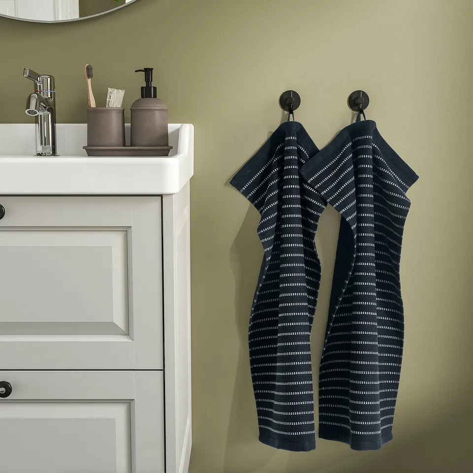 Green bathroom with BROKGINST towels on hooks above white sink.