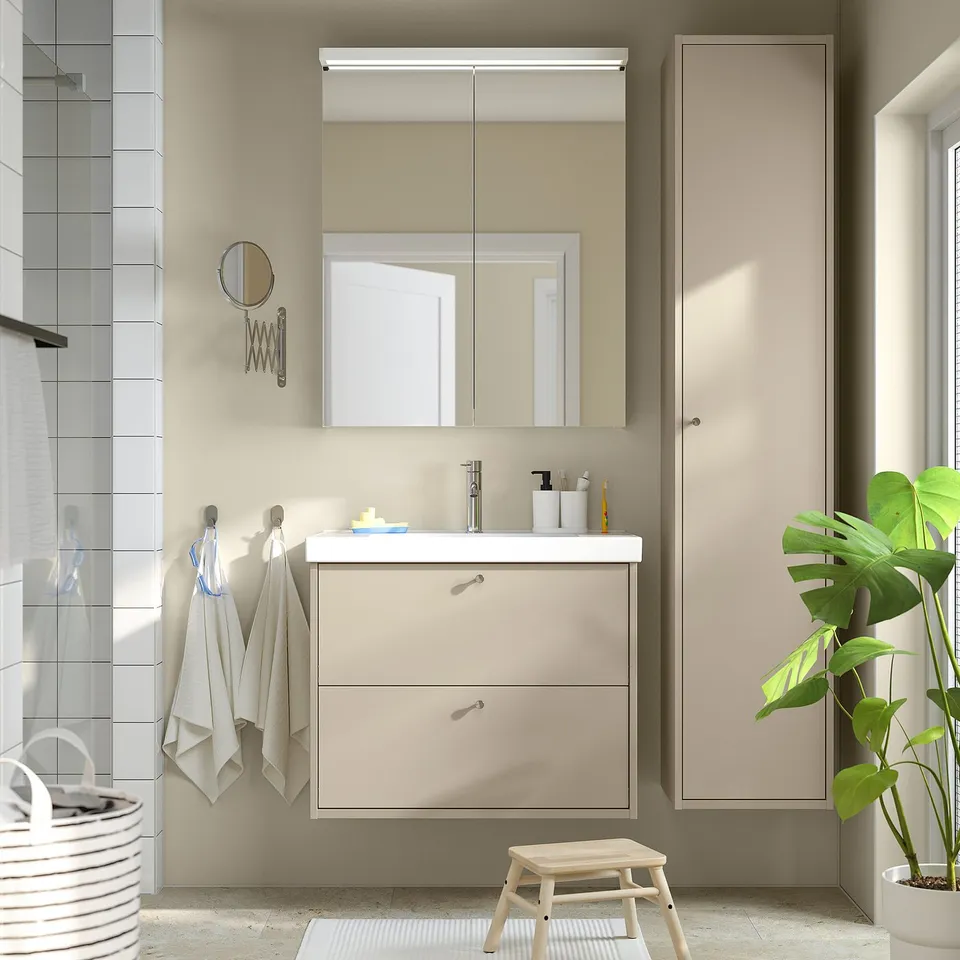 Modern bathroom with beige HAVBÄCK vanity, white sink, mirror, and green plant.
