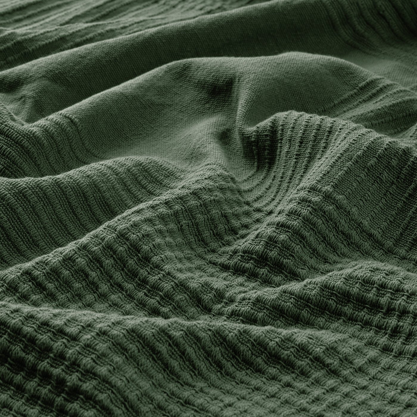 Dark green woven cotton bedspread, texture visible, tightly knit for warmth and comfort.