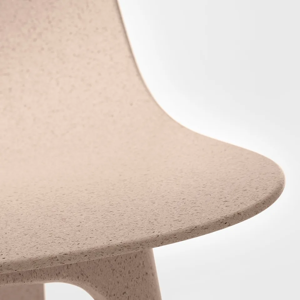 Close-up of ODGER chairs smooth, textured seat. Shows soft, moulded plastic with wood fibres, offering comfort and durability.
