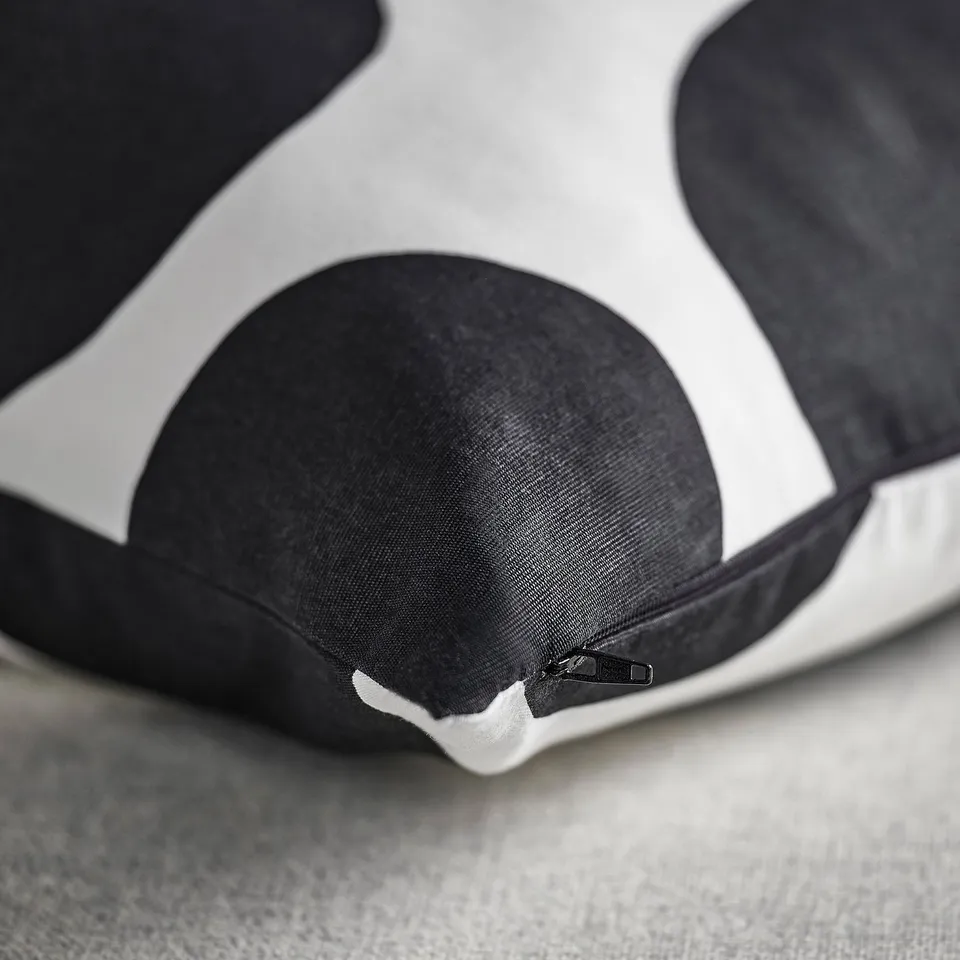 Close-up of a soft, black, and white dot-patterned cushion cover with a hidden zip, showing its quality texture and design.