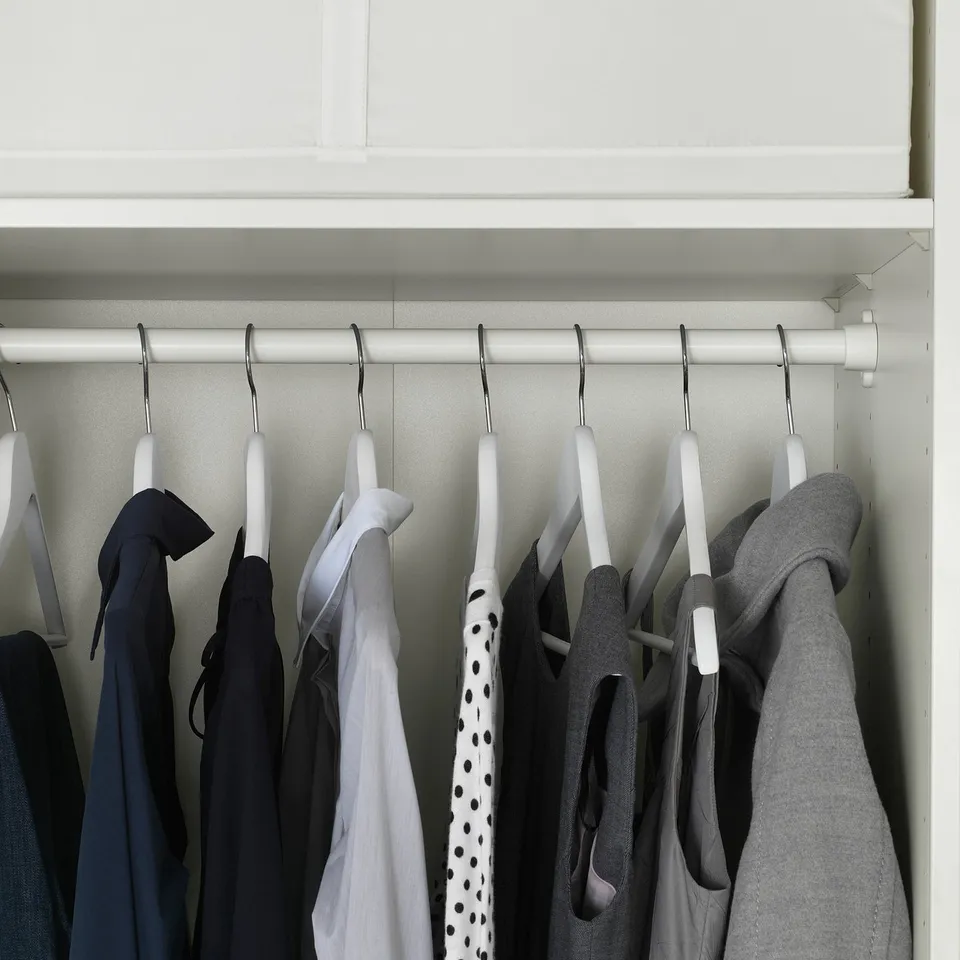 Closet rail holding clothes, featuring multiple hangers with various garments.