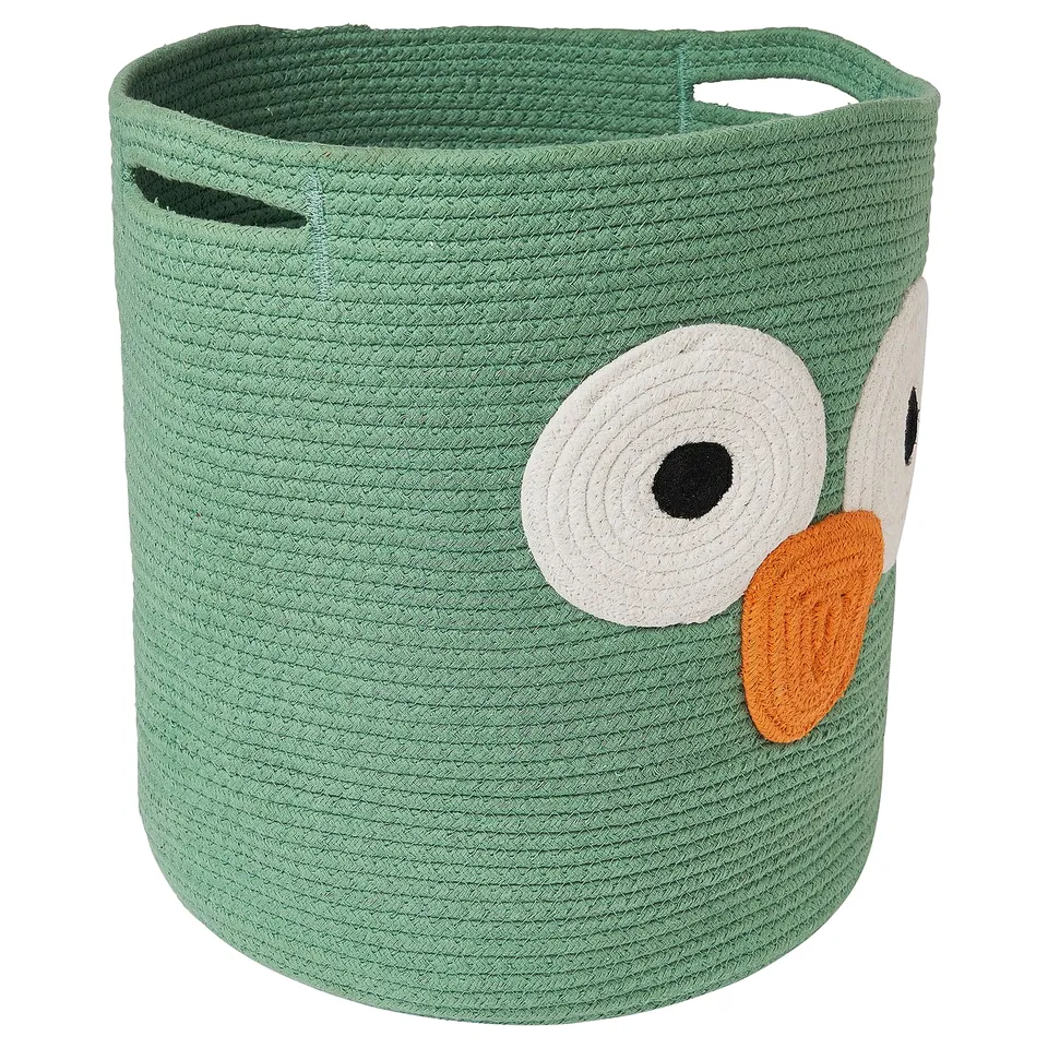 A green UPPSTÅ storage basket in the shape of an owl, made from braided cotton. The owl has large white eyes, an orange beak, and black details.