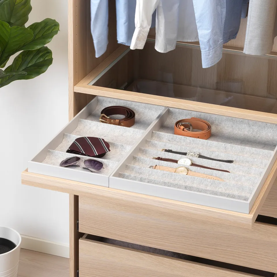 Wooden drawer organiser with felt compartments holds ties, belts, and watches, slides out smoothly.