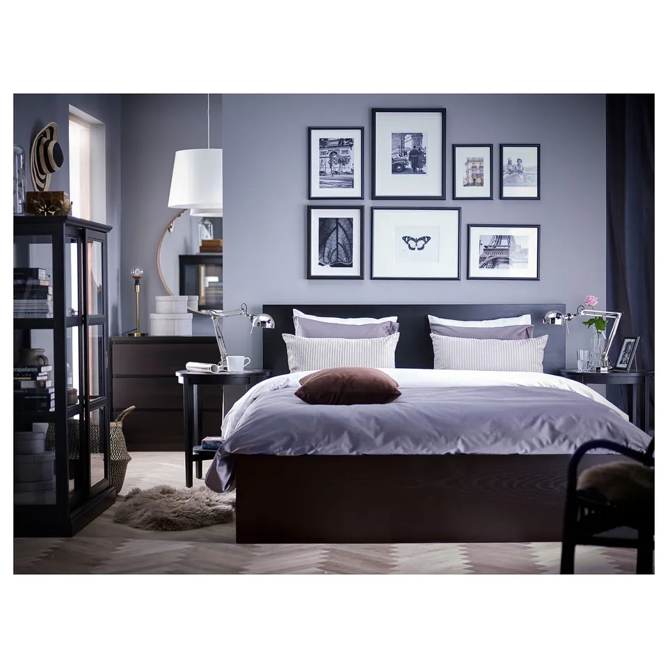 Grey bedroom with dark wood MALM bed, purple pillows, gallery wall, & black nightstands.