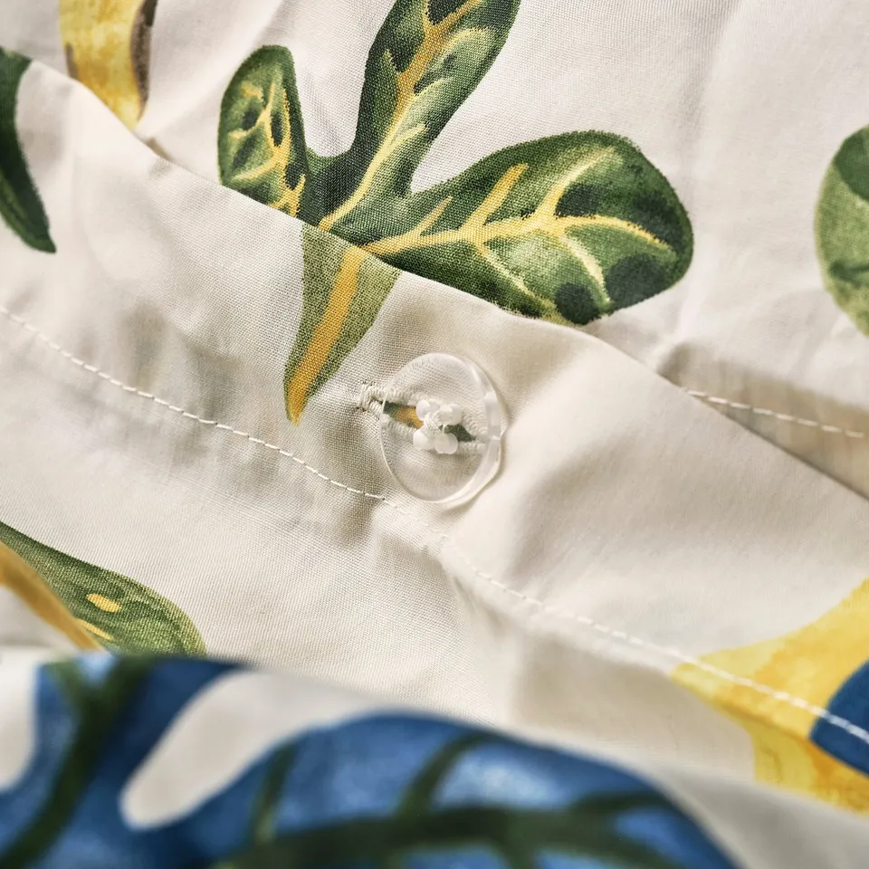 Button closure detail with embroidered border on floral-patterned duvet.