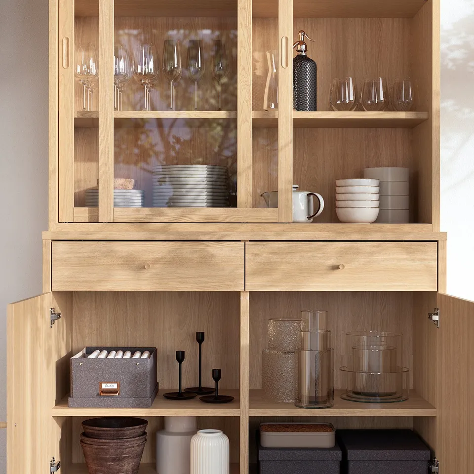 Wooden glass-door cabinet displays dishes, glasses, and vases. Soft-close drawers and adjustable shelves.