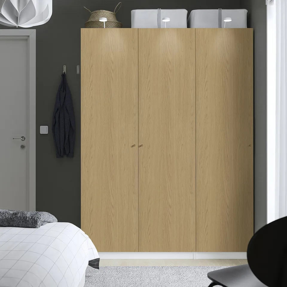 The is: modern bedroom featuring a large wooden PAX wardrobe, matching grey decor, and minimalist furniture.
