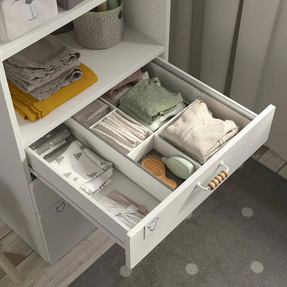 Neatly organised baby clothes and accessories in a white SMÅSTAD bookcase drawer, showcasing efficient storage and easy access.