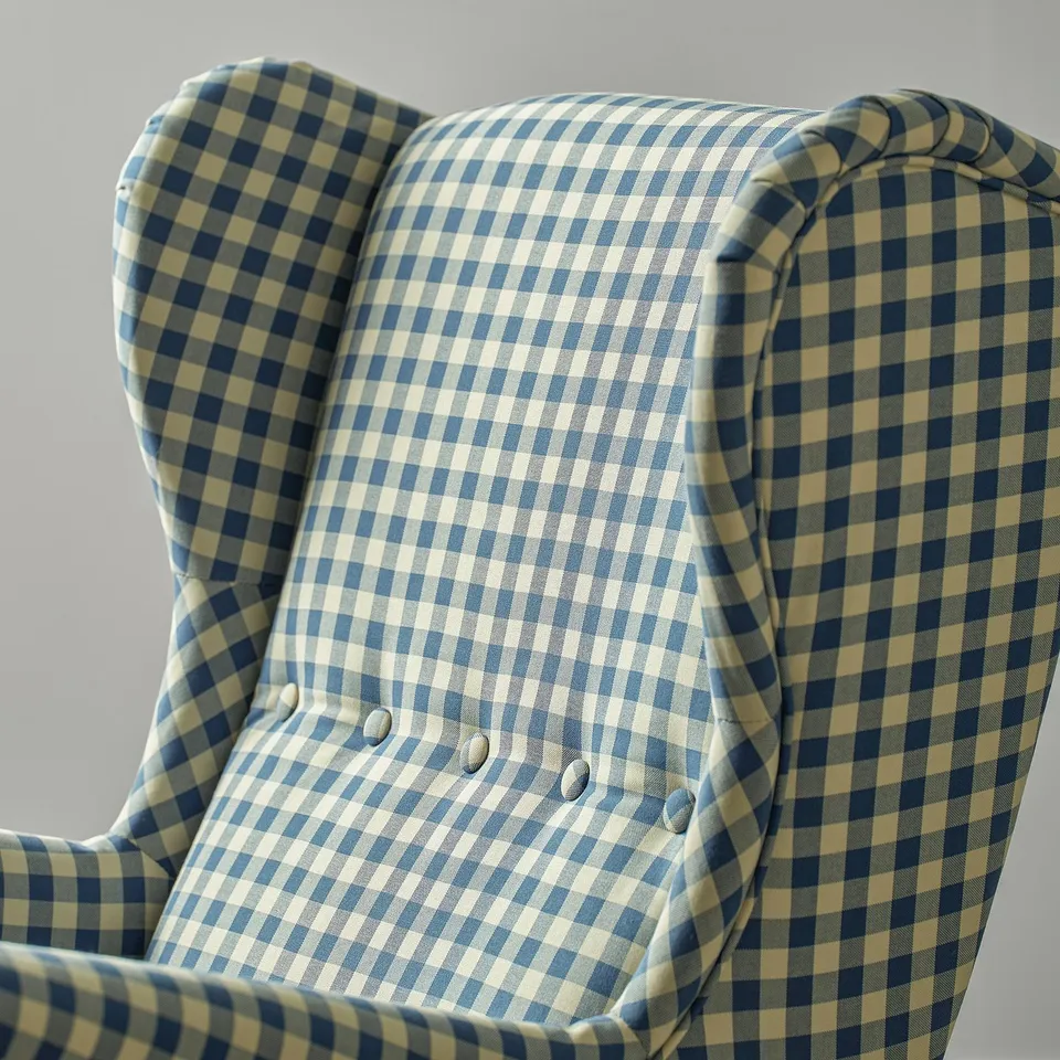 A comfy, checked wingback chair with high back and armrests, upholstered in blue and white fabric.