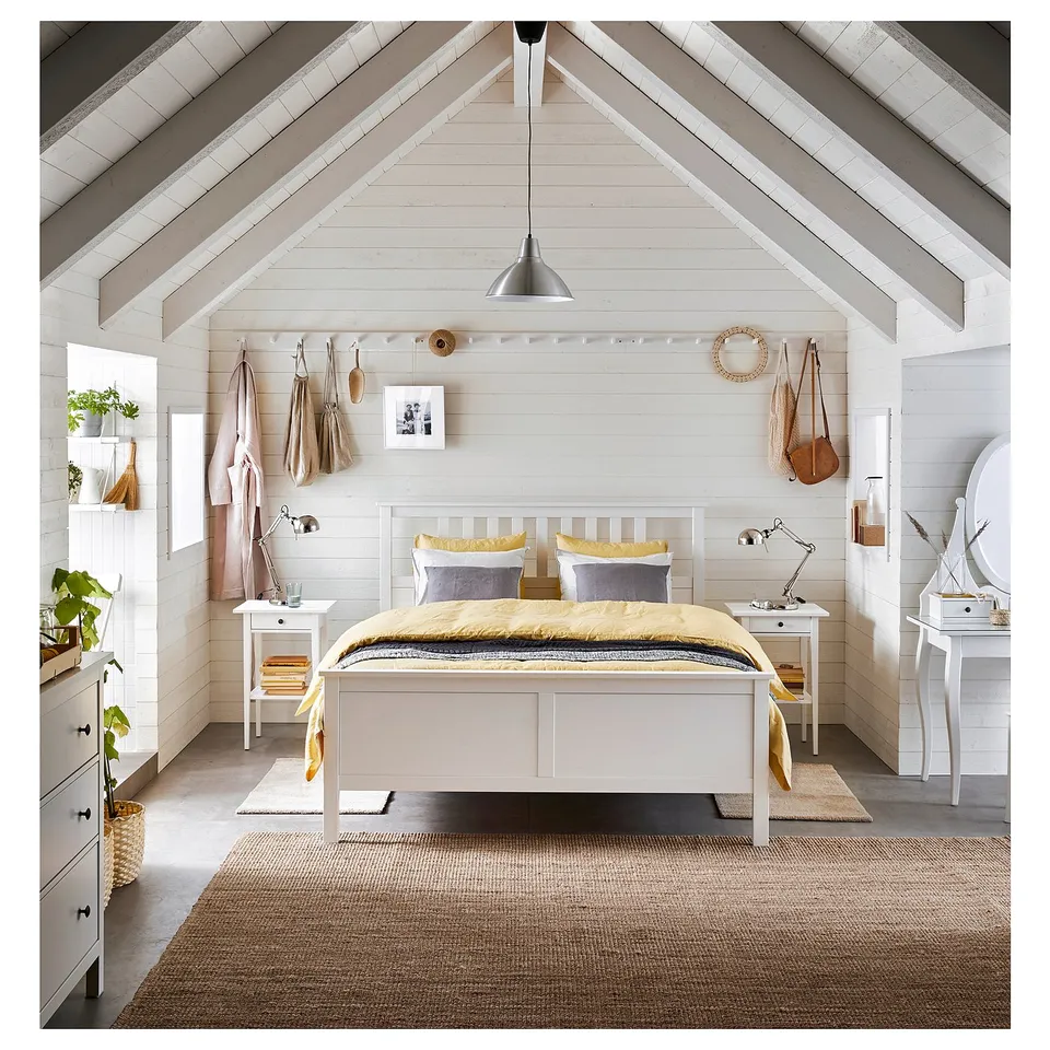 Cosy white bedroom with yellow-gray bed, nightstands, dresser, and plant.