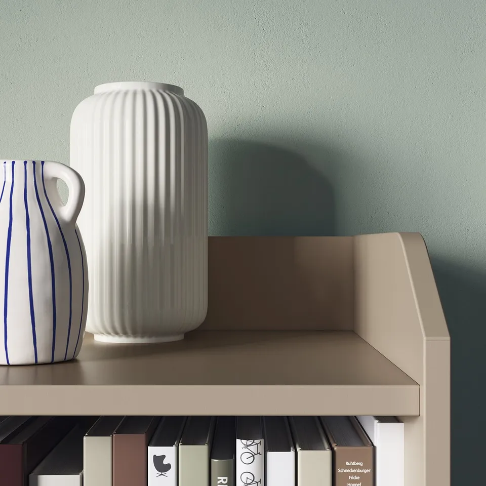 Two white vases, one ribbed and one striped, displayed on a beige shelf against a mint wall.