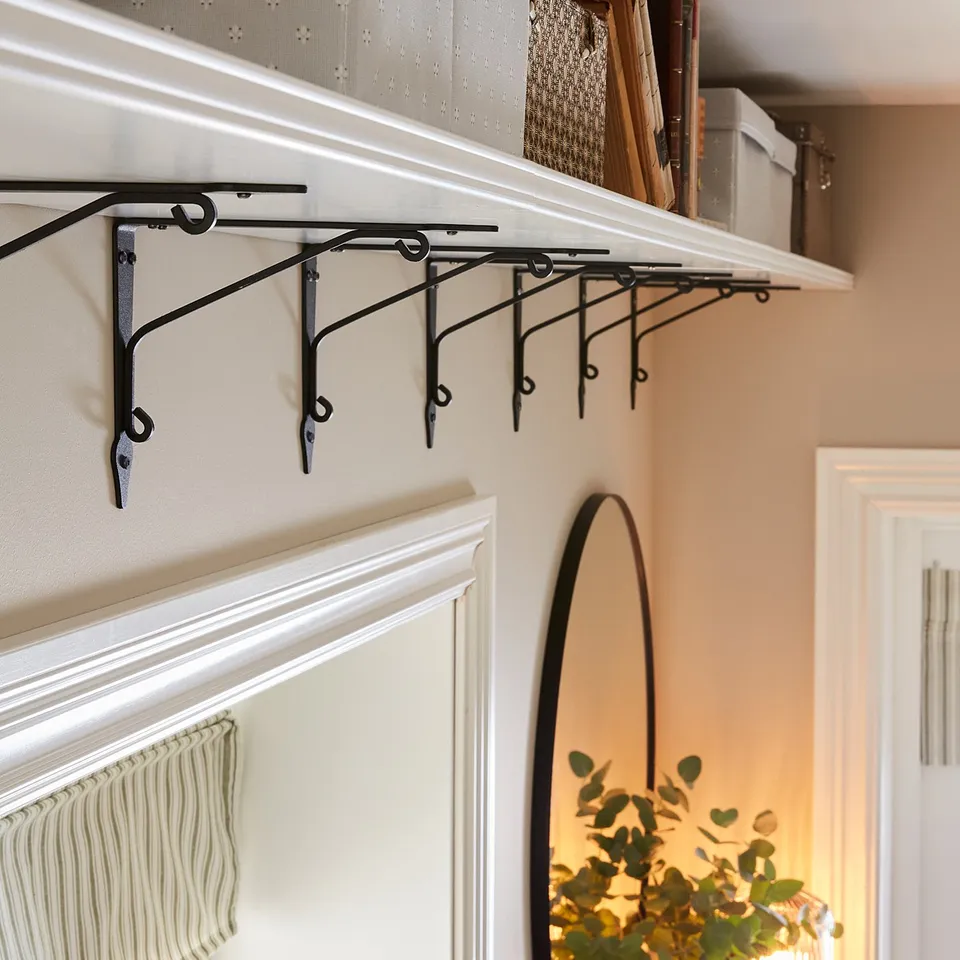 A white shelf with black brackets holds storage boxes and files.
