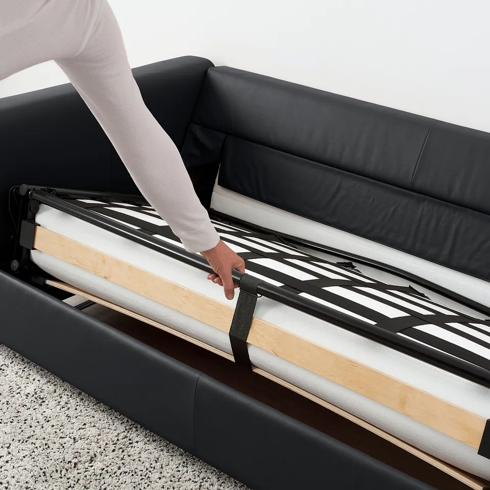 Person setting up VIMLE sofa-bed frame, transforming sofa into bed.
