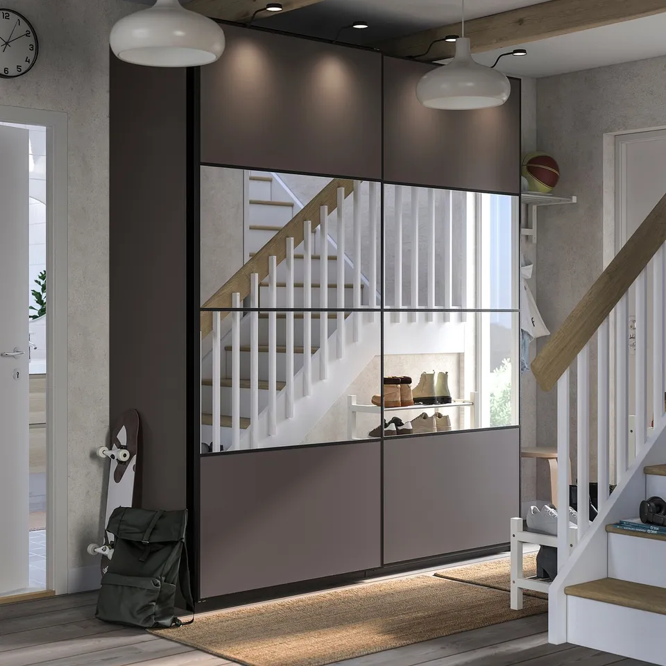 Modern entryway with mirrored & wooden sliding doors, stairs, rug, backpack, skateboard, and shelves.