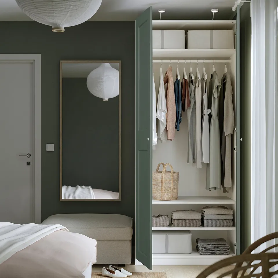 Open wardrobe with clothes hangers, folded clothes, boxes, and a wicker basket.