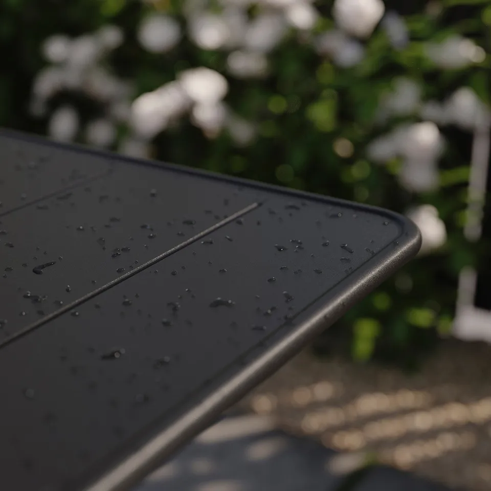 Black, foldable outdoor table with water drops; modern design, ideal for small spaces.