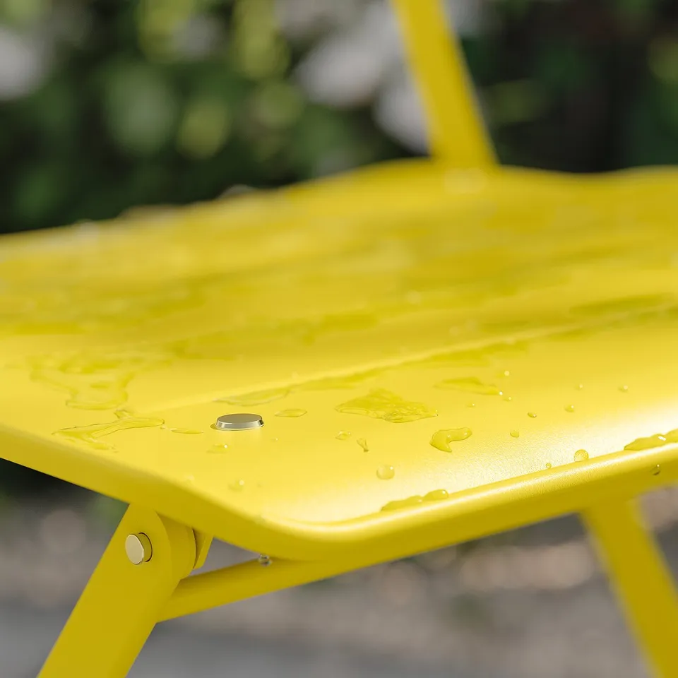 Bright yellow foldable metal garden table with water droplets, set outdoors.