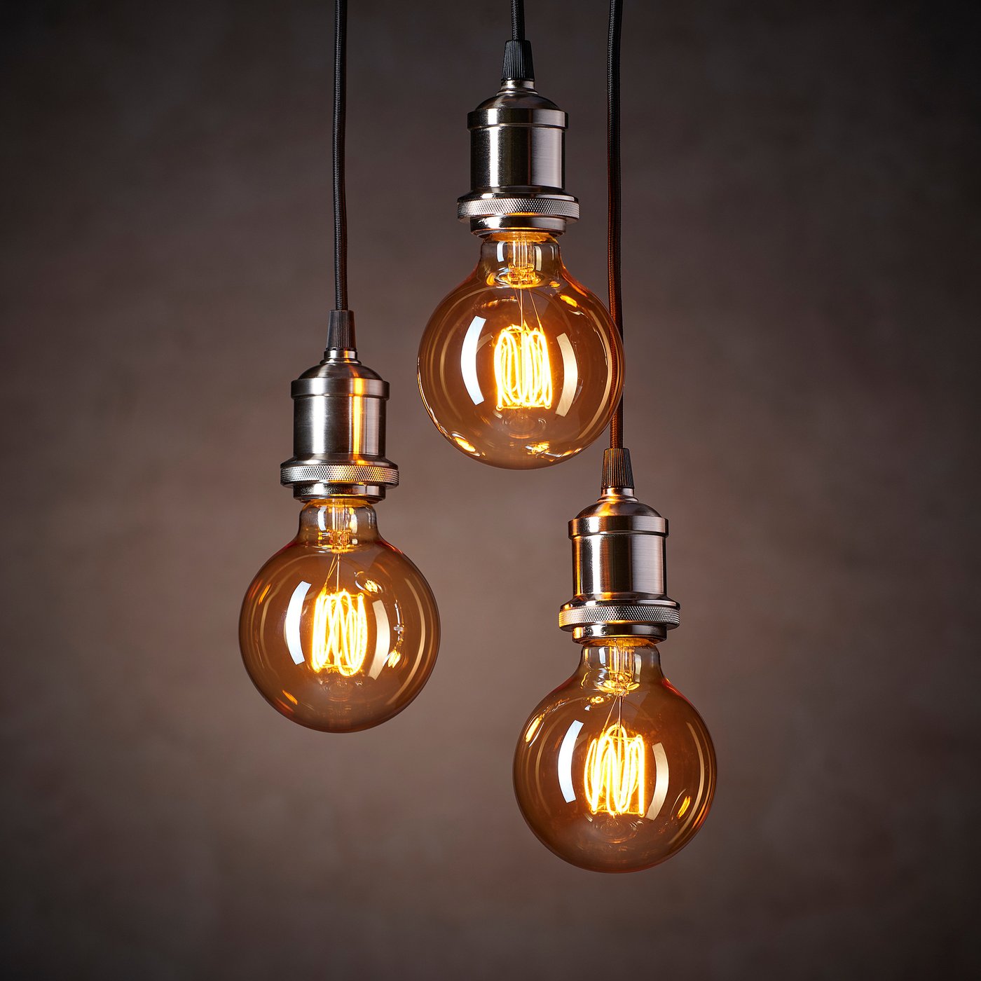Three vintage-style light bulbs with warm amber glow hang from cords, emitting cosy light.