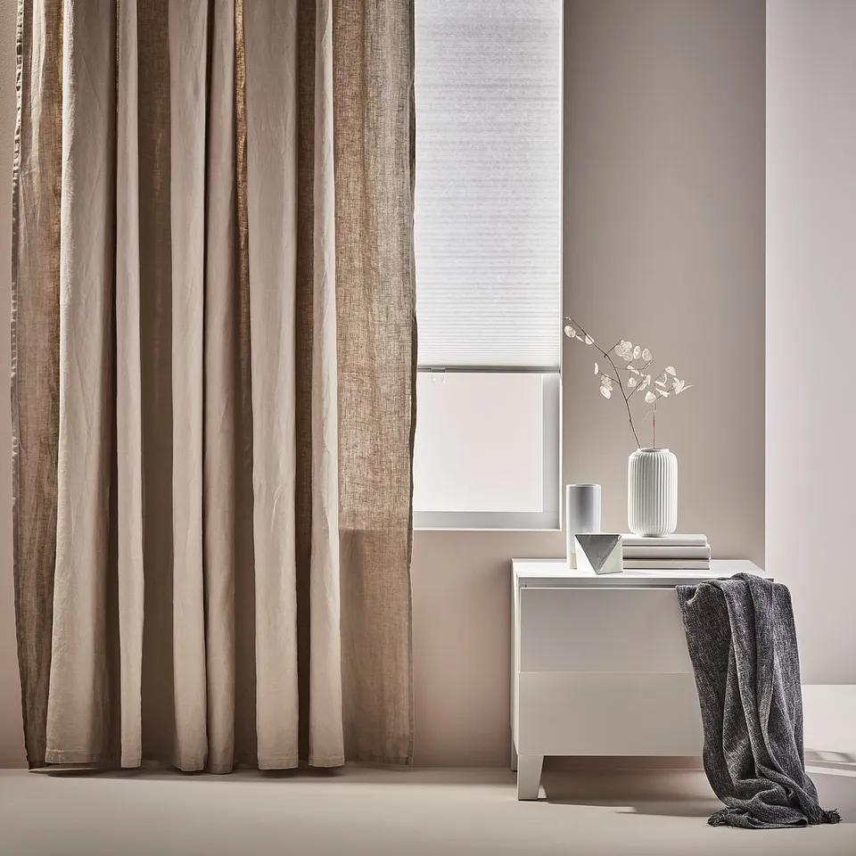 Modern neutral living space, featuring beige curtains, PLATSA white console, grey throw, and styled with books and vase.