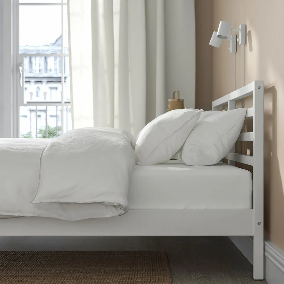 Cosy bedroom with TARVA bed, pillows, blanket, and large window.