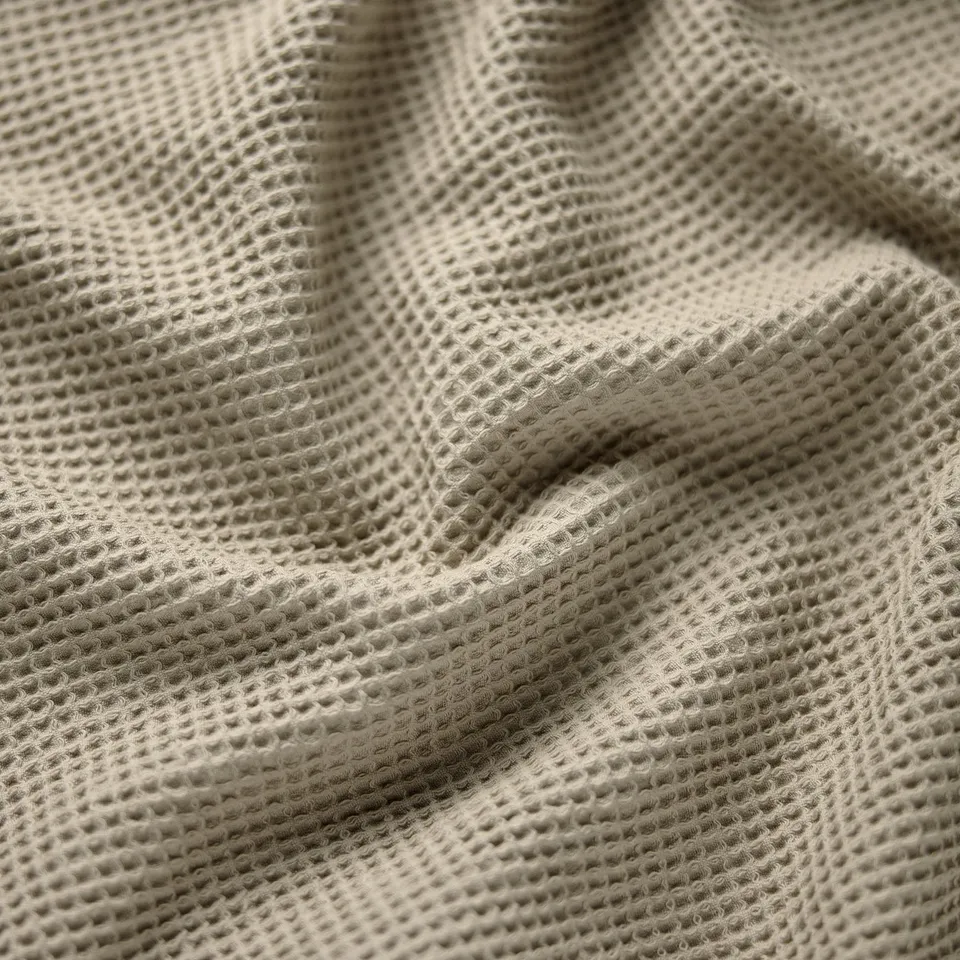 Close-up of a textured towel with a waffle weave pattern, highlighting its softness and durability.