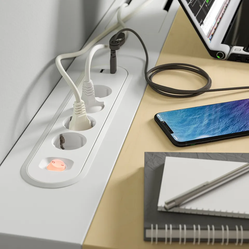 White MITTZON desk with visible plug sockets, connected devices, and a smartphone.