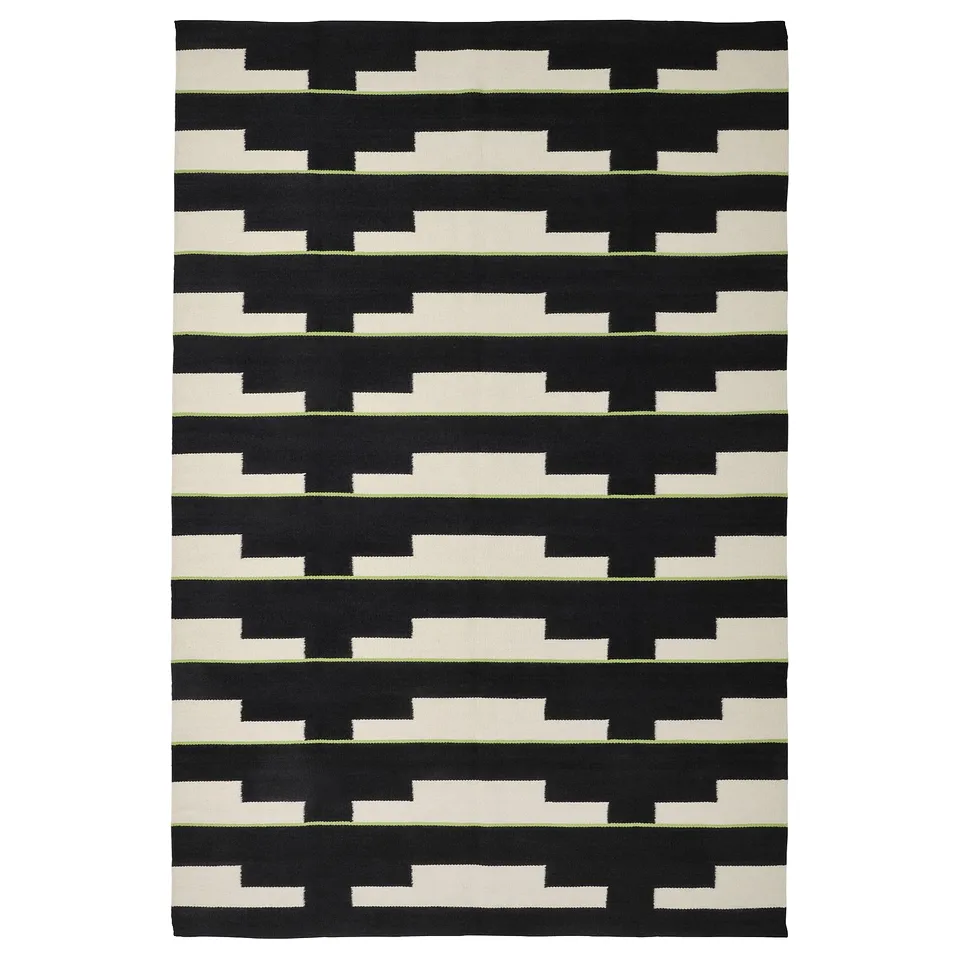 A black and white geometric, handwoven wool rug named STOCKHOLM 2025, featuring a repeating pattern, reversible design.