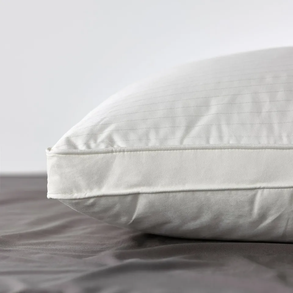 Close-up of a premium pillow featuring fine dobby weave and double piping, displaying its supportive and luxurious design.