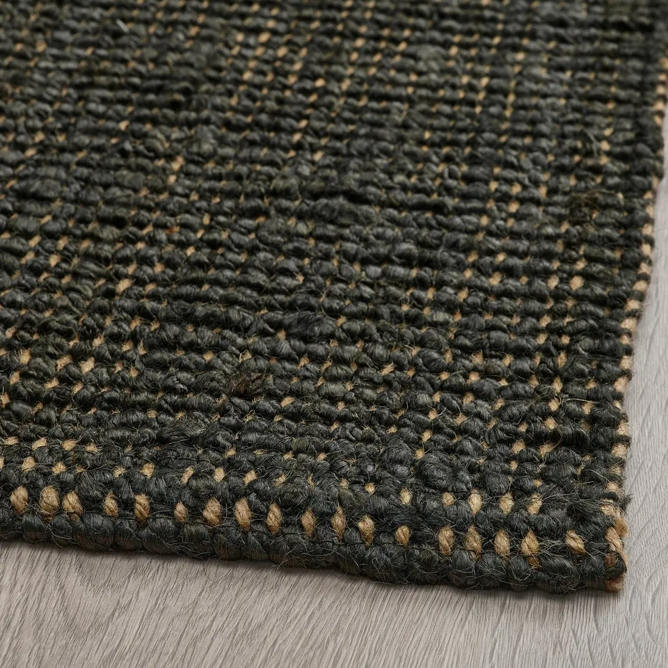 Dark green jute rug with intricate weave texture on a wooden floor. Natural fibres create a rustic, cosy look.