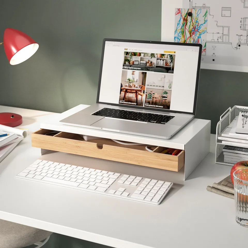Modern white desk setup with laptop, wireless keyboard, red lamp, and ELLOVEN stand holding the laptop.