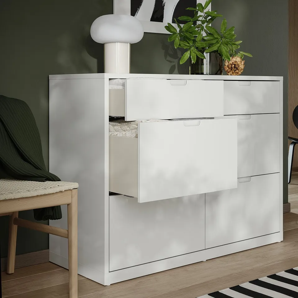 White TONSTAD chest with 6 drawers, modern design, green backdrop, lamp, plant, chair.