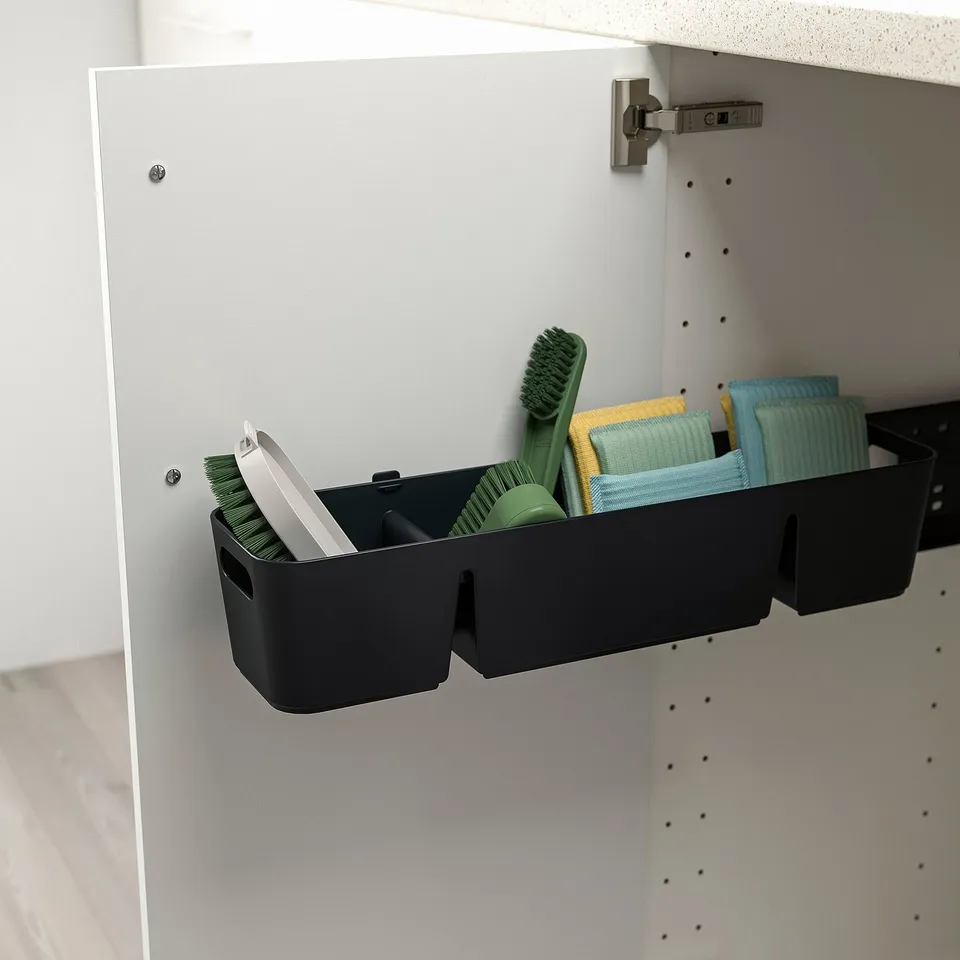 Black cabinet organiser holding green brushes and sponges, attached inside a white cabinet.