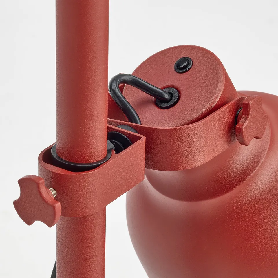 Red adjustable lamp with robust metal design, featuring individual light controls and height adjustment mechanisms.