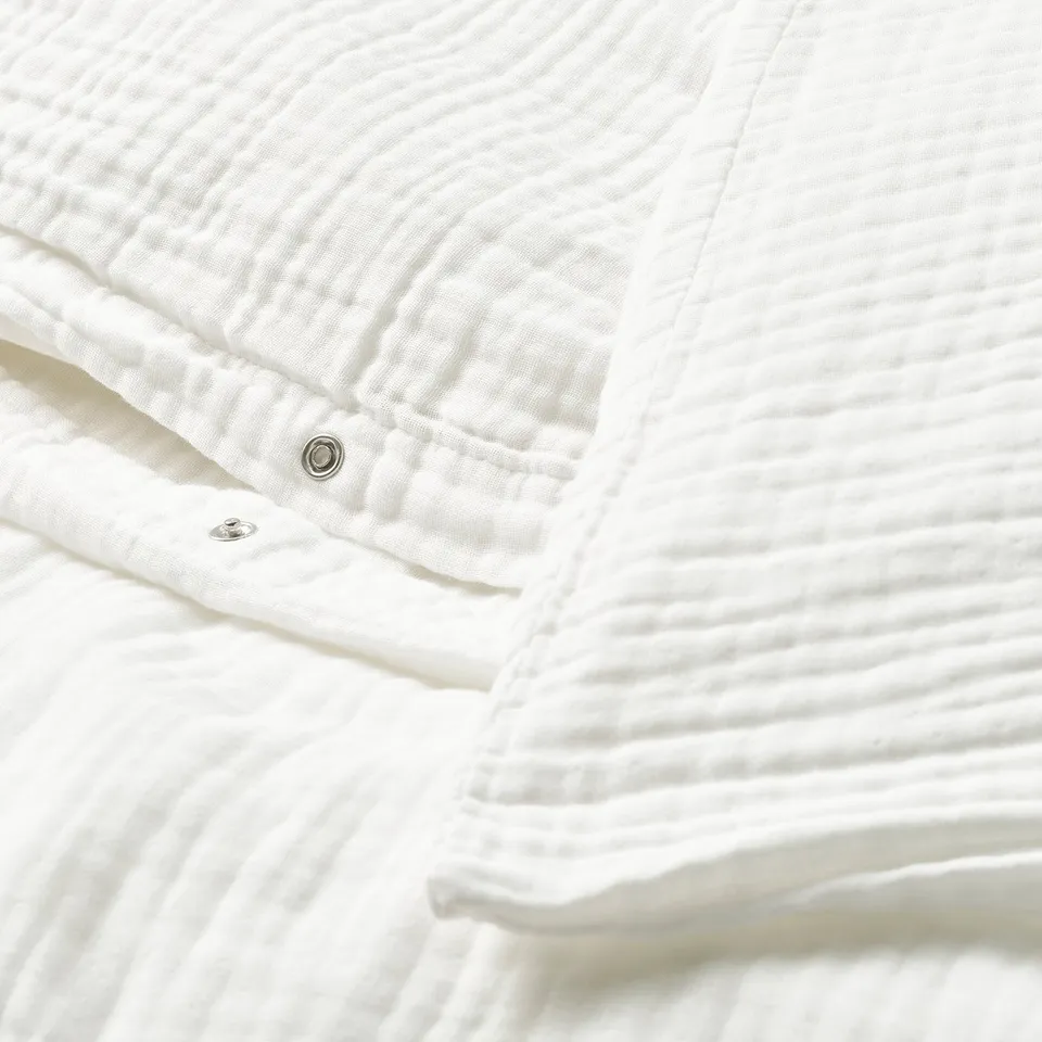 Close-up of white duvet cover with snap closure, showing soft, textured fabric.