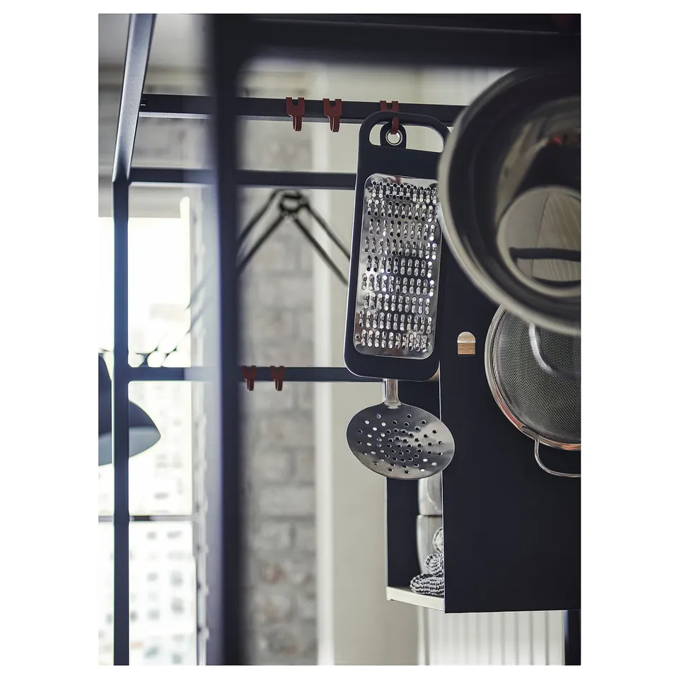 Black metal kitchen tool rack with hanging utensils.