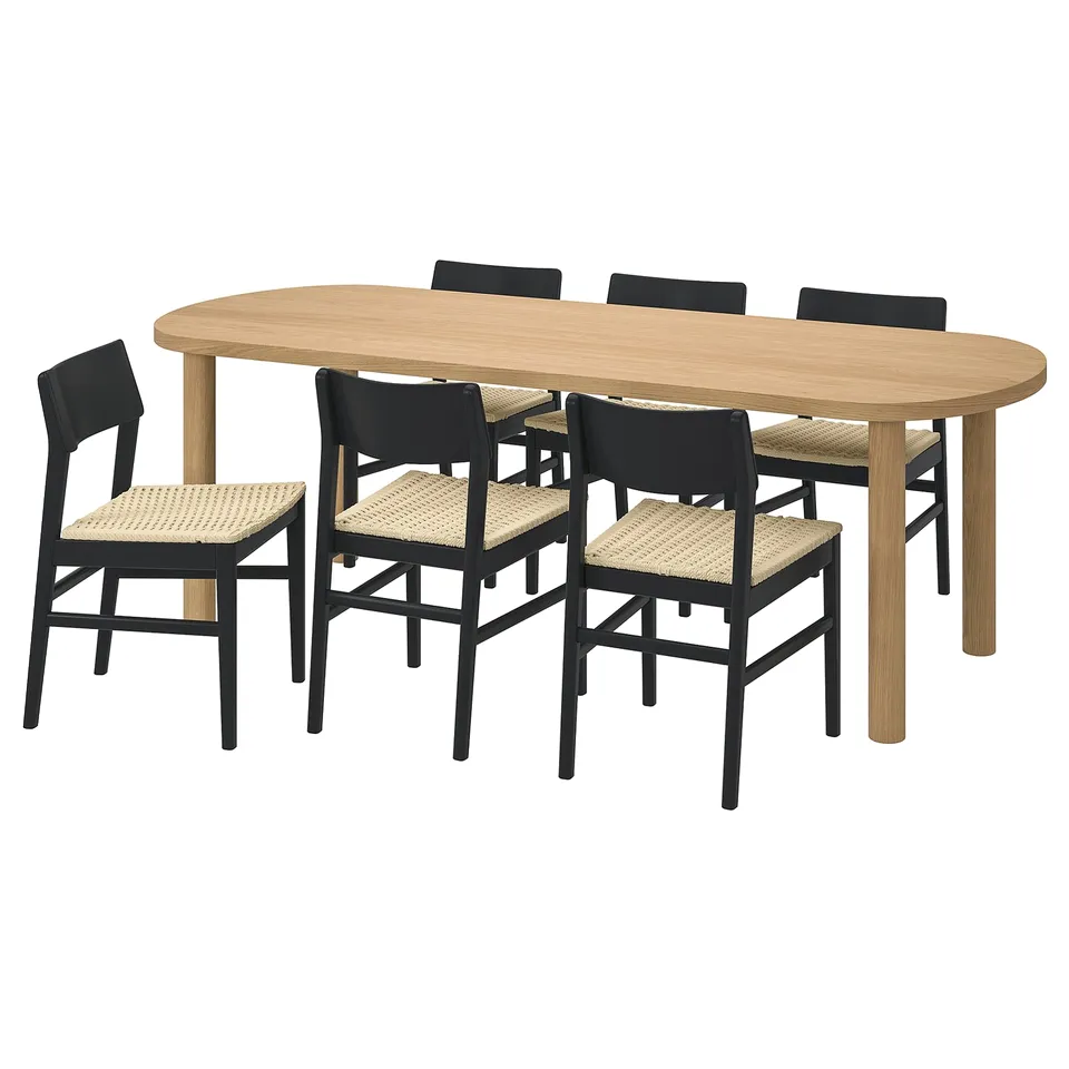 Dining set with oval table and dark chairs. Oak wood, woven seats, sleek design.