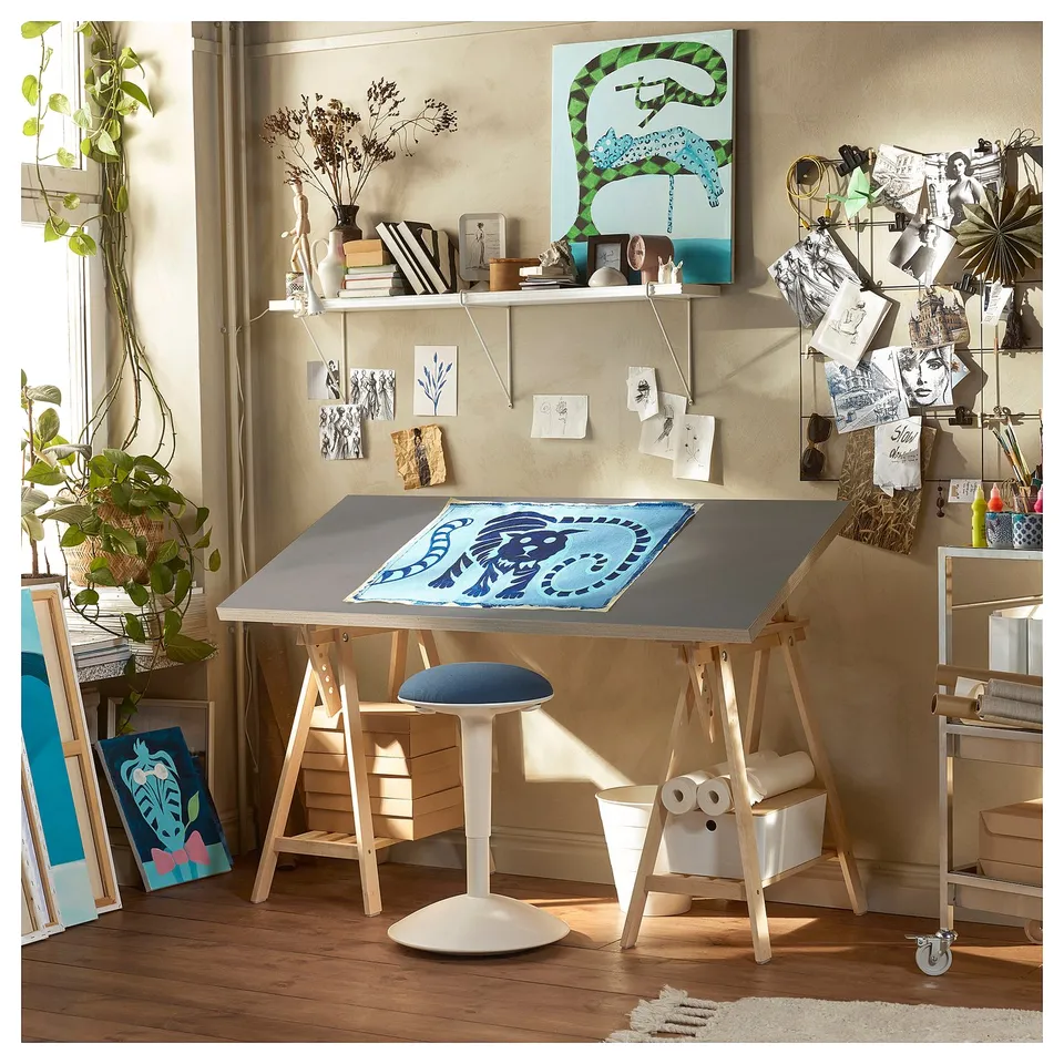 Bright studio with LAGKAPTEN desk, wooden legs, blue art, plants & decor.