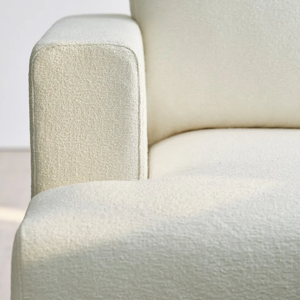 Close-up of cream sofa armrest, showcasing plush, textured fabric and sturdy stitching.