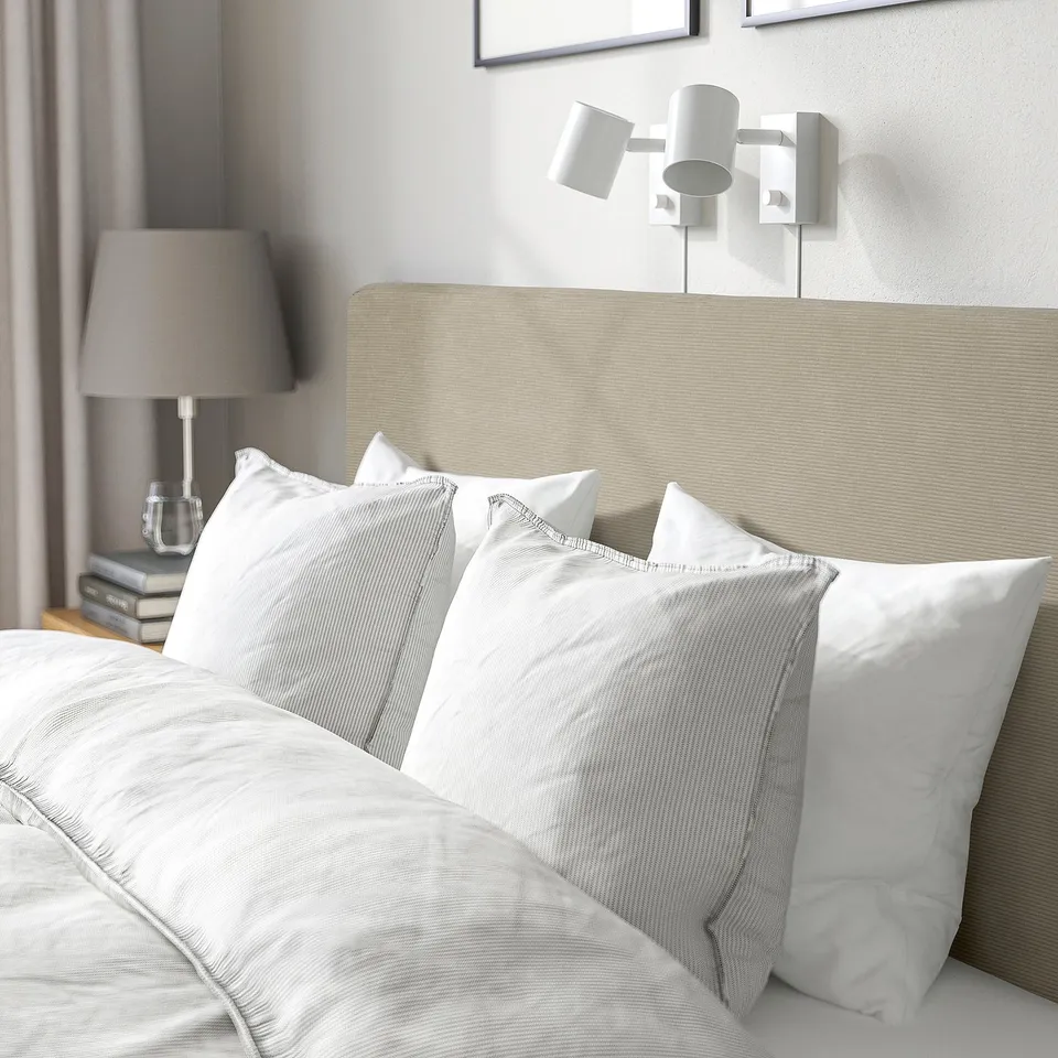 Bed with soft, padded headboard, white linens, bedside table with lamp, and wall lights.
