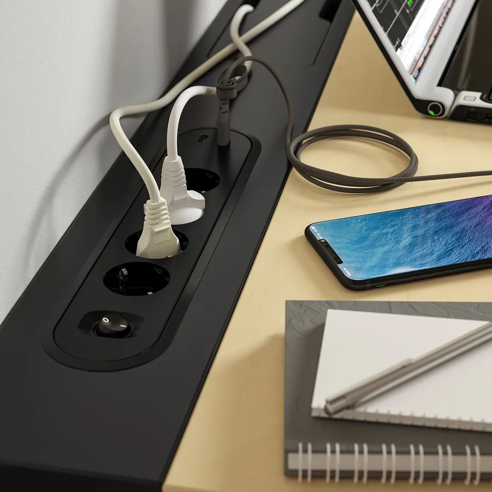 Modern desk with power outlets and usb ports, a smartphone, and a notebook, promoting efficient work setup.