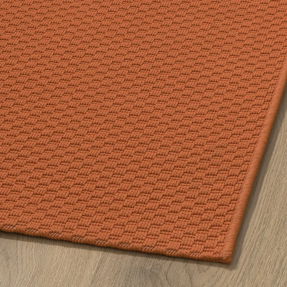 Close-up of orange textured MORUM rug, showcasing its durable, tightly woven fabric.