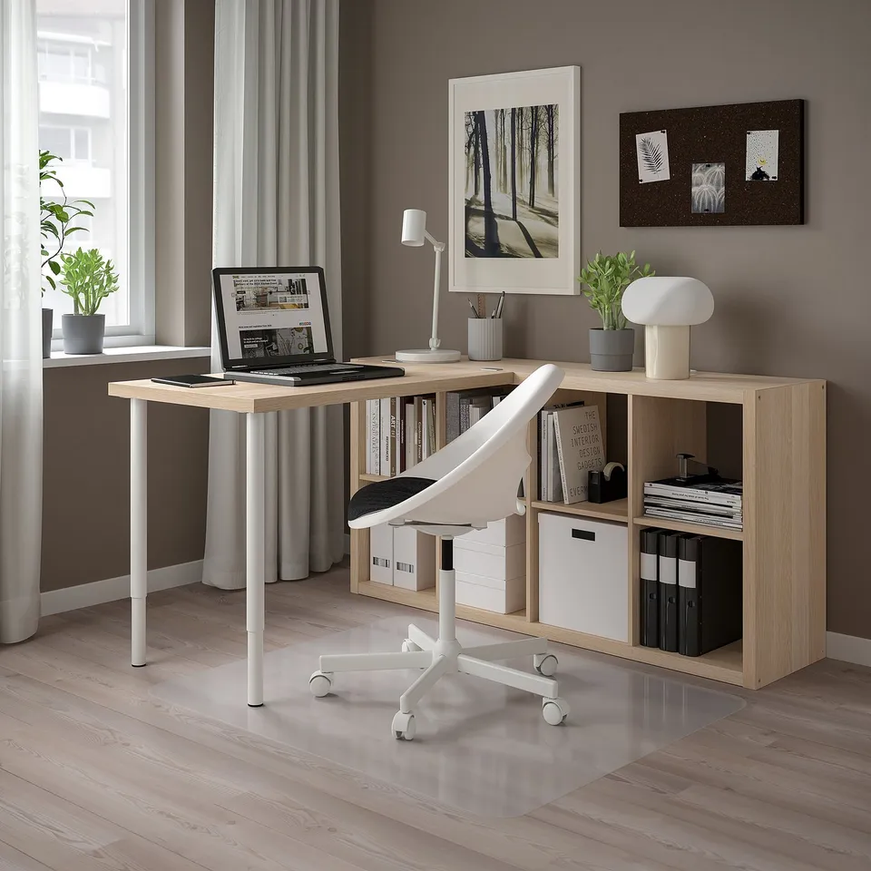 Modern home office with KALLAX storage, adjustable desk, laptop, bookcase, ergonomic chair, plants, minimalist decor.