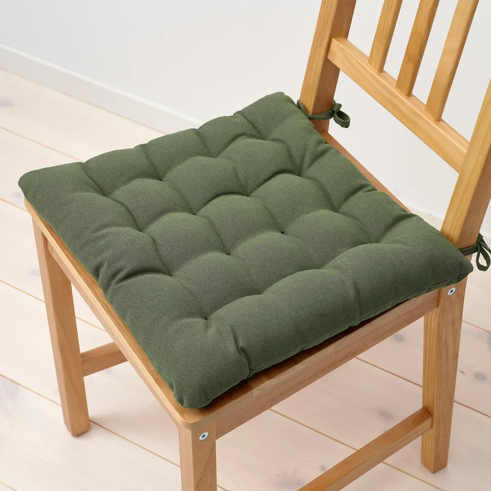 Green tufted chair pad on wooden chair. Thick, cushioned, with ties to secure.