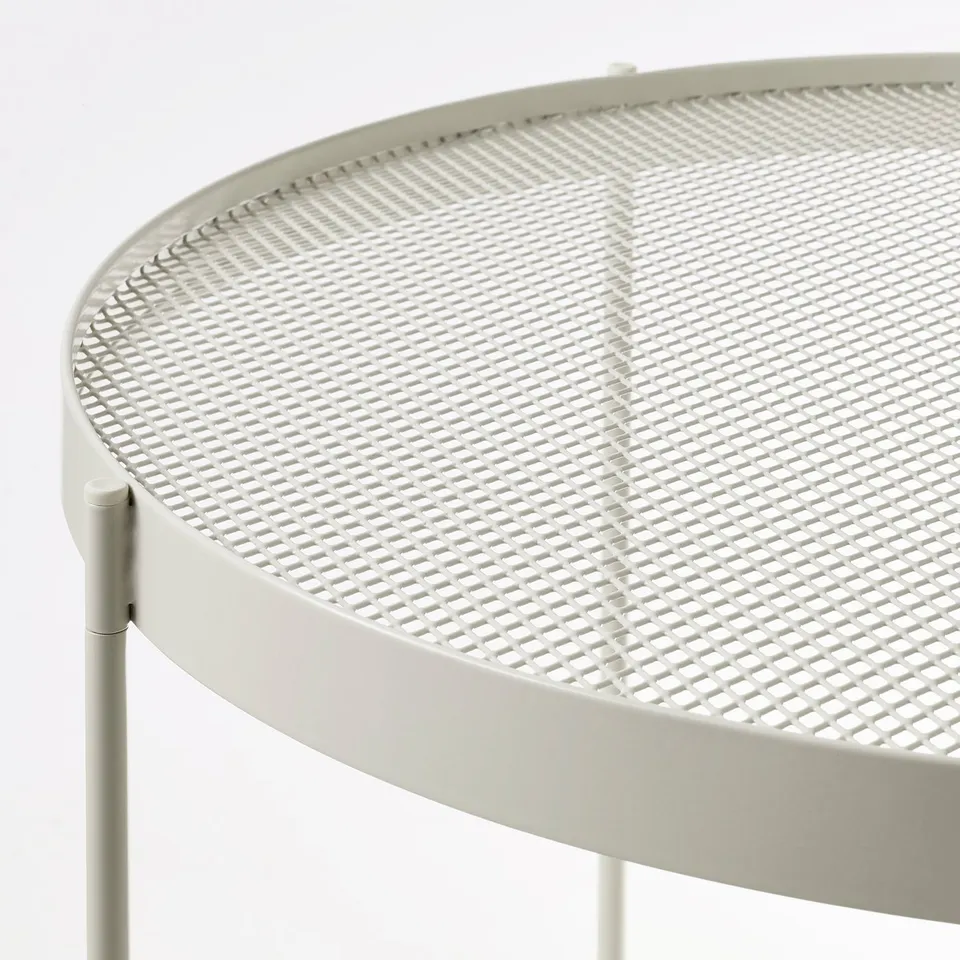 Circular mesh table with raised edge, light-colored.
