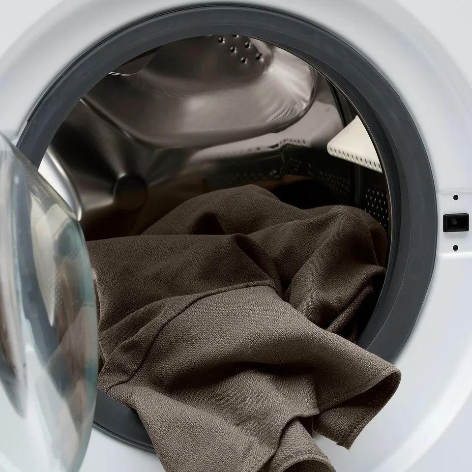 Washing machine door open, showing a dark fabric inside.